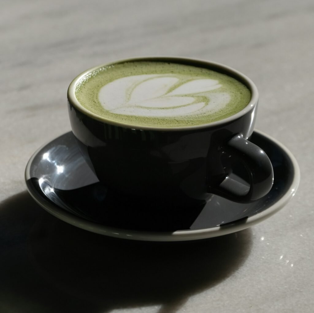 A matcha latte in a dark cup on a pale marble surface